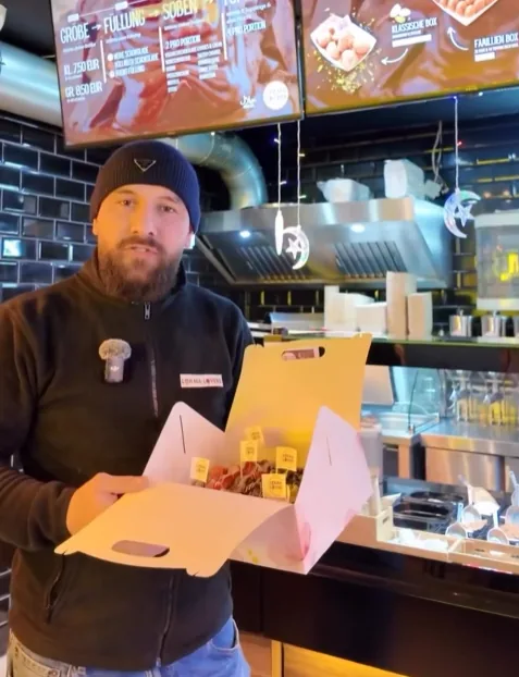 Mitarbeiter von Lokma Lovers hält eine Box frischer Lokma an der Theke